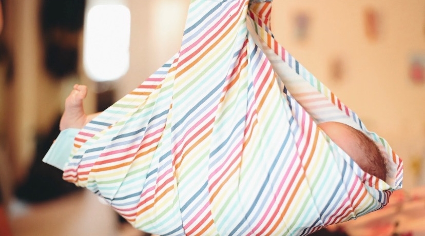 A newborn being weighed in a sling.