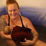 Thumbnail: A mother smiles as she holds her newborn.