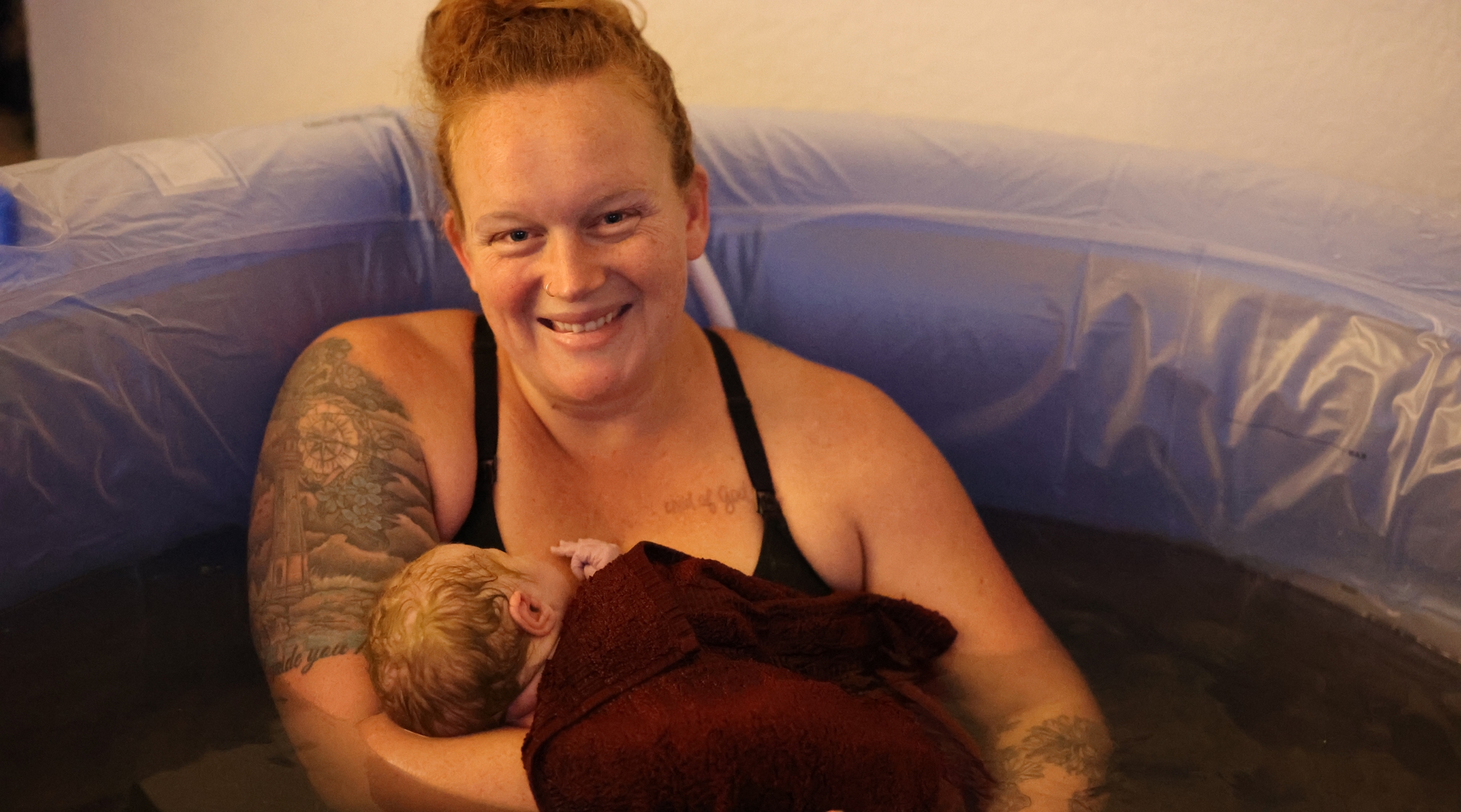 A mother smiles as she holds her newborn.