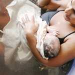 Thumbnail: A mother holds her newborn in a birth tub.