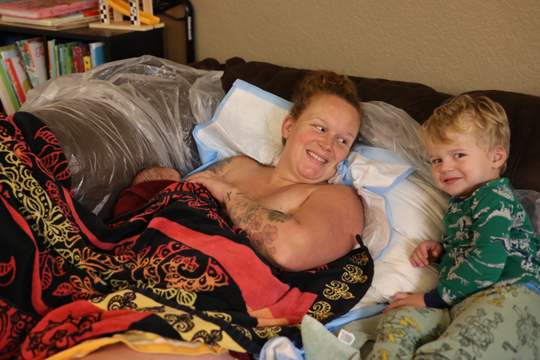 Mother and son rest while new baby nurses.